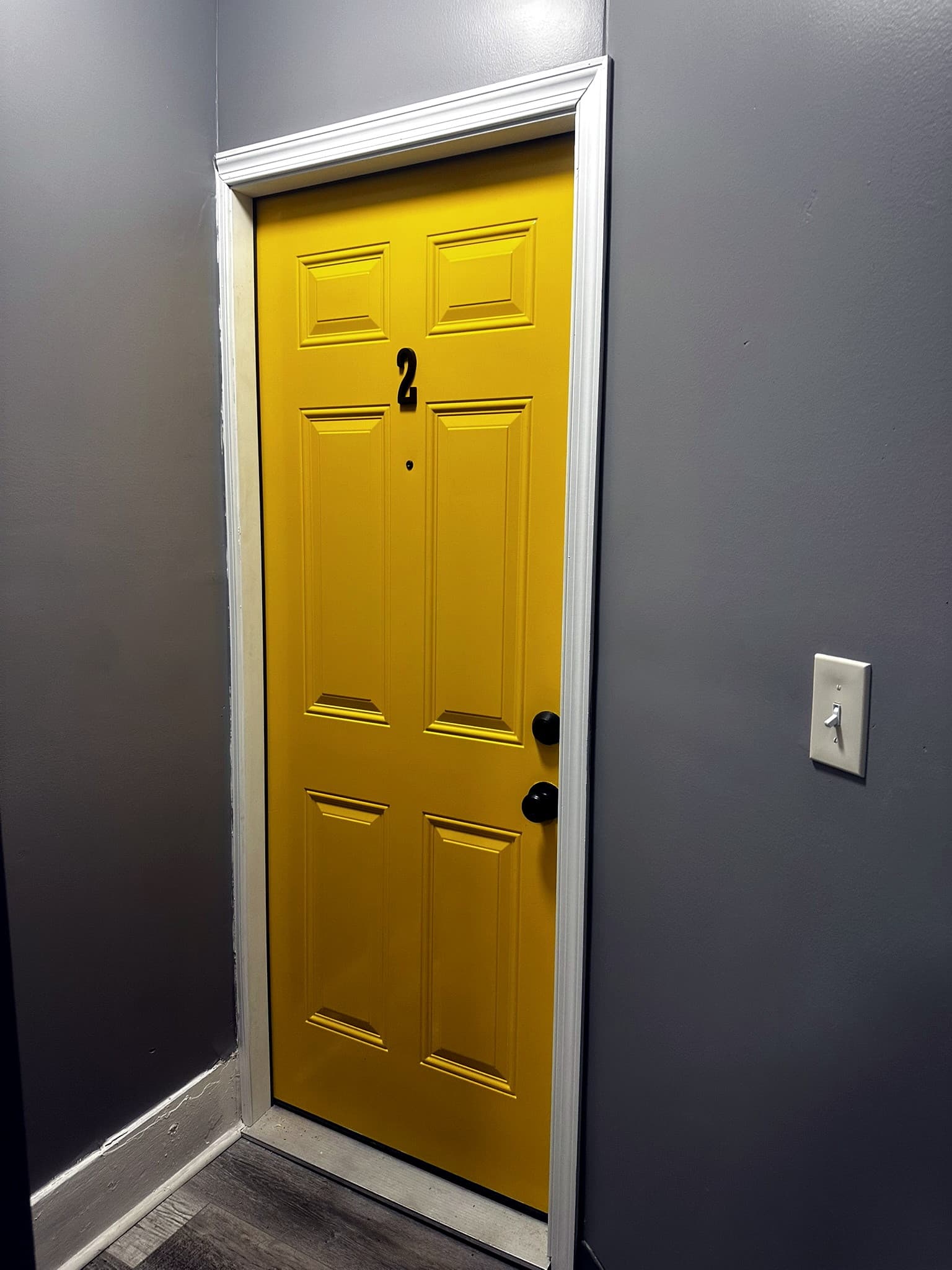 Yellow entry door marked 2, set in a gray hall.